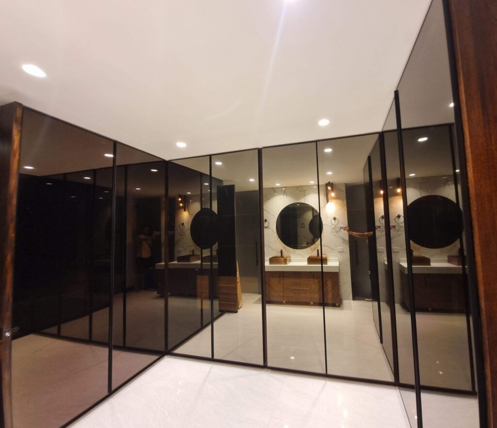 Puertas de vidrio de piso a techo enmarcadas en nogal americano macizo, closet de lujo hecho a la medida por Alterra Craft en Tucson, AZ
