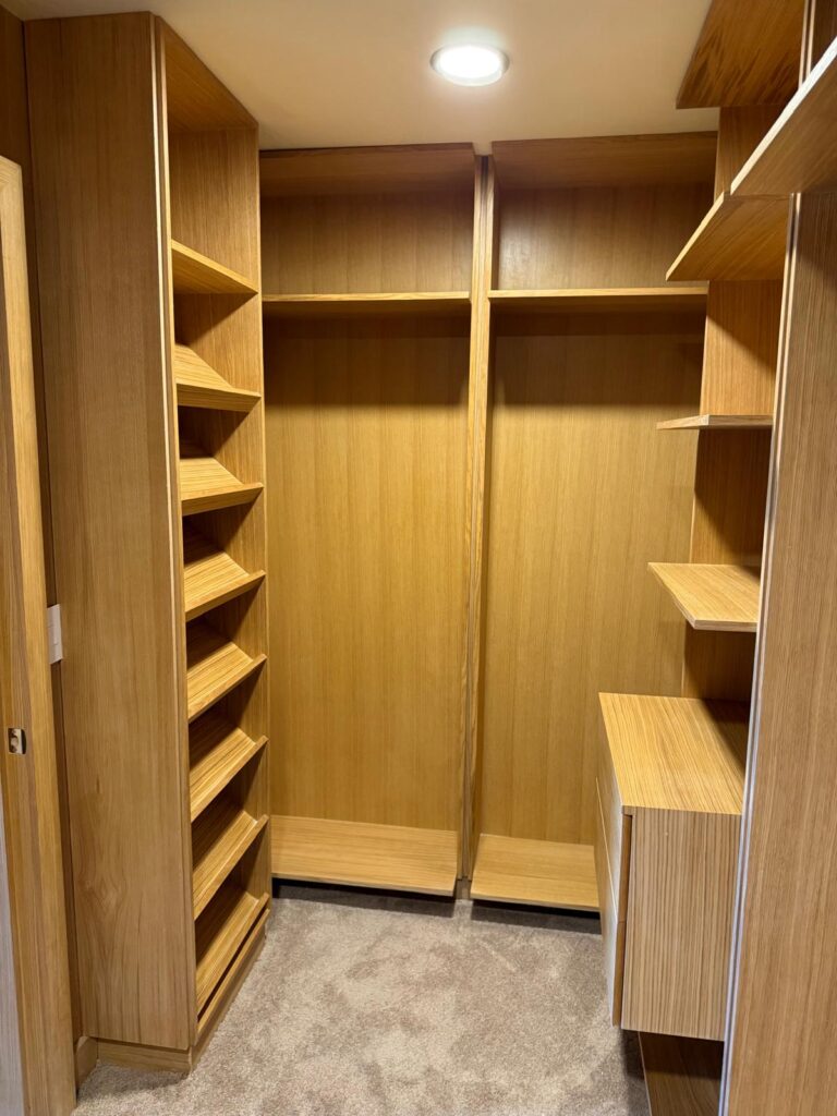 Custom walk-in closet in wood-grain melamine with angled shoe shelves, open hanging space, and a drawer unit, precision-built by Alterra Craft in Tucson, AZ