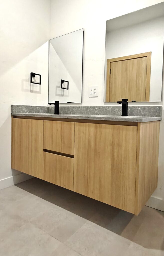 Modern floating bathroom vanity in wood-grain melamine with dual matte black faucets, custom cabinetry in Tucson, AZ