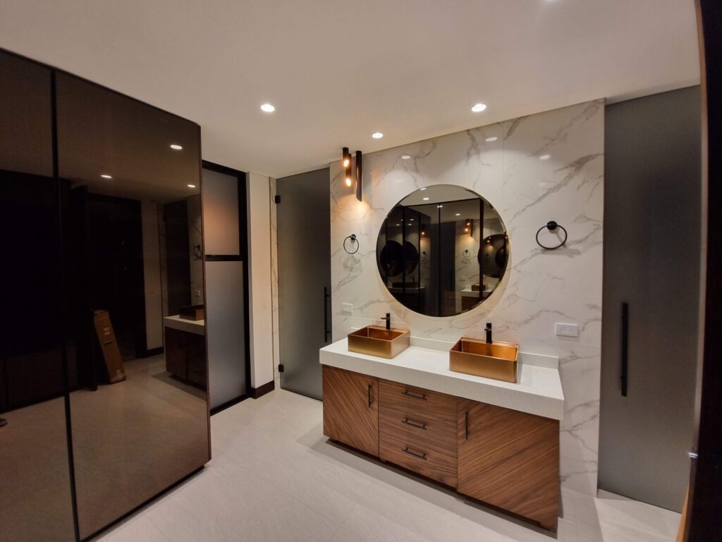Luxury contemporary master bathroom vanity in American walnut with frosted black glass doors, quartz countertop, integrated LED lighting, and custom copper vessel sinks